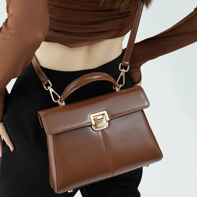 Women's black leather shoulder bag with clasp closure and adjustable strap showing interior organisation