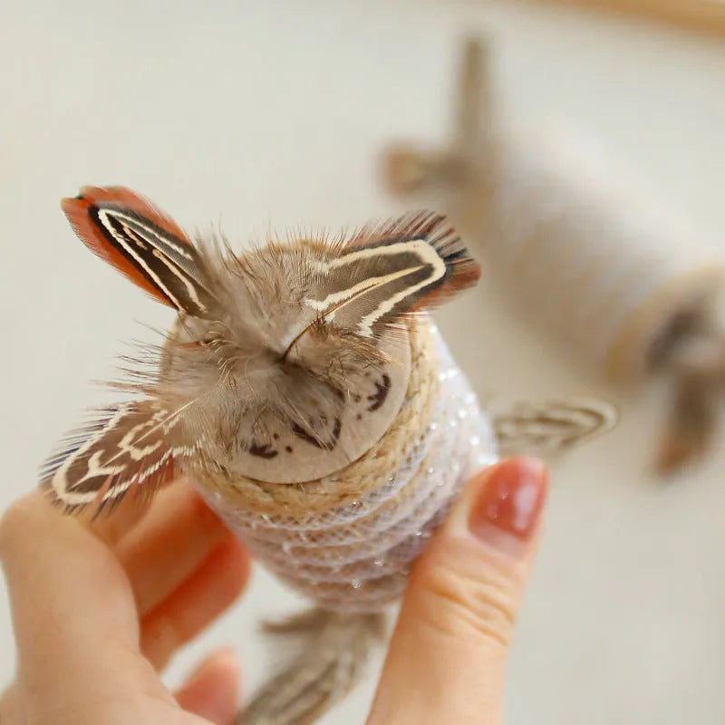 Beige interactive cat feather wand toy with hemp rope scratching surface and a catnip ball.