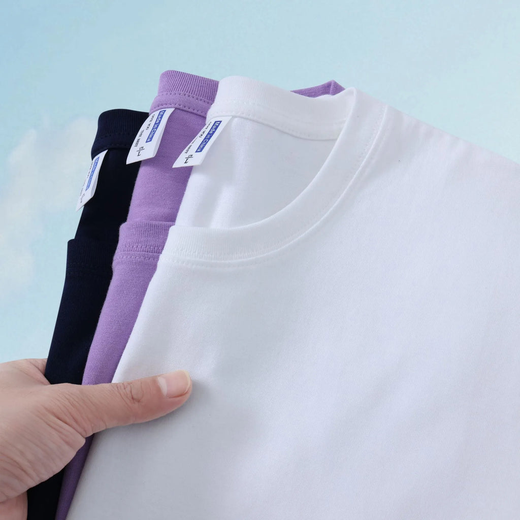 Men's and women's loose-fit cotton T-shirt in solid colours like navy blue, red, and white, shown as a short-sleeve pullover top.