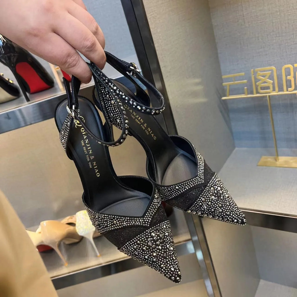 Women's black hollow high heel with stiletto heel, pointed toe, and red sole on a light background.