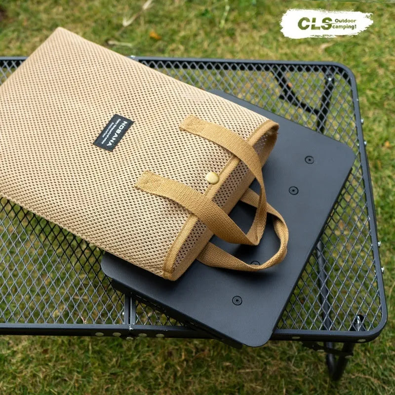 Aluminium folding stool set up as a small table with a beige PU mat cushion, next to its storage bag.
