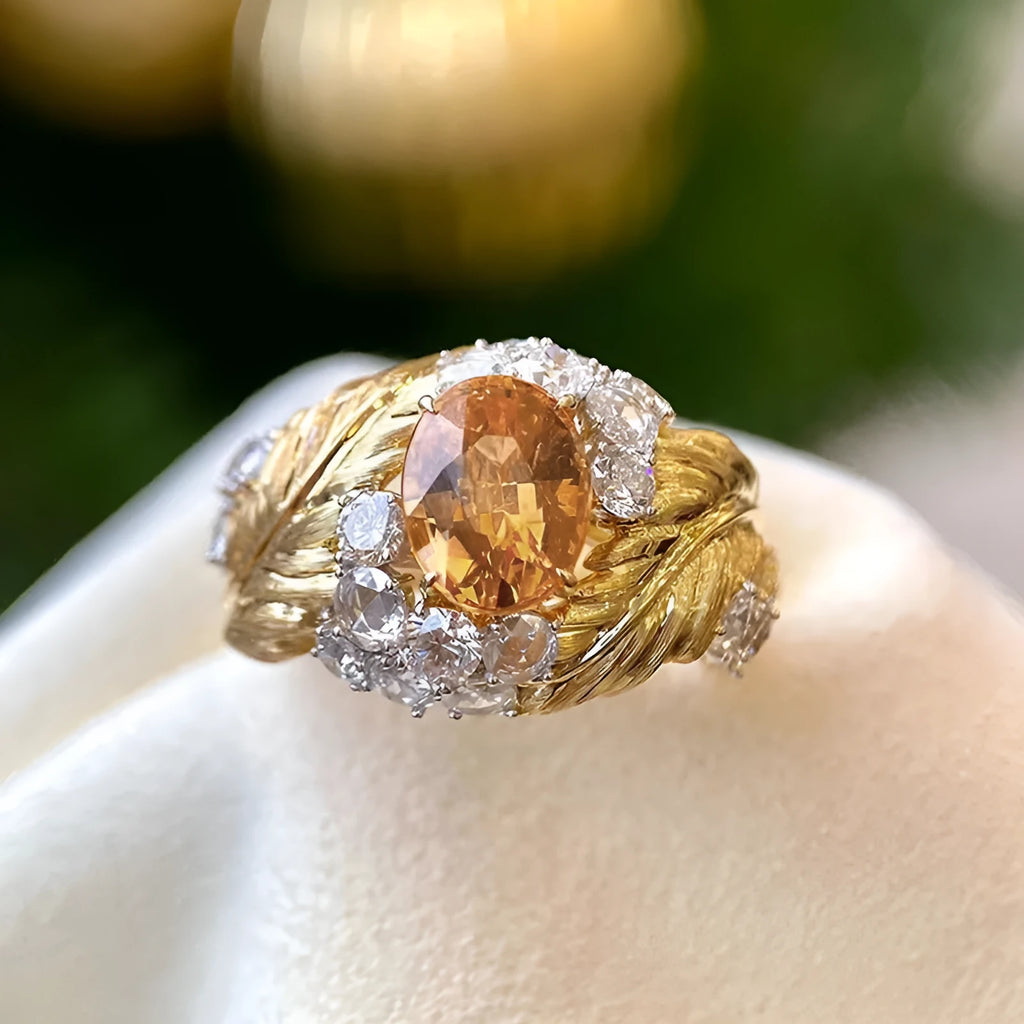 Gold women's ring with embossed feather pattern and a yellow zircon stone on a geometric copper band.