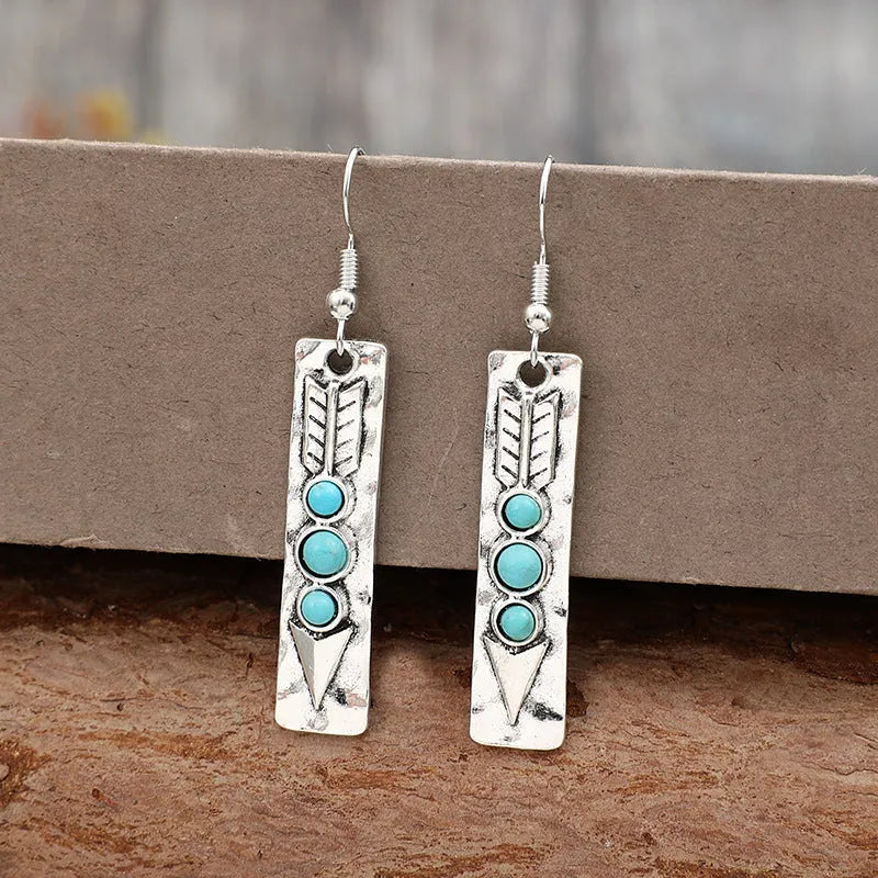 Geometric silver earrings with turquoise inlay pattern and retro styling on long strip design