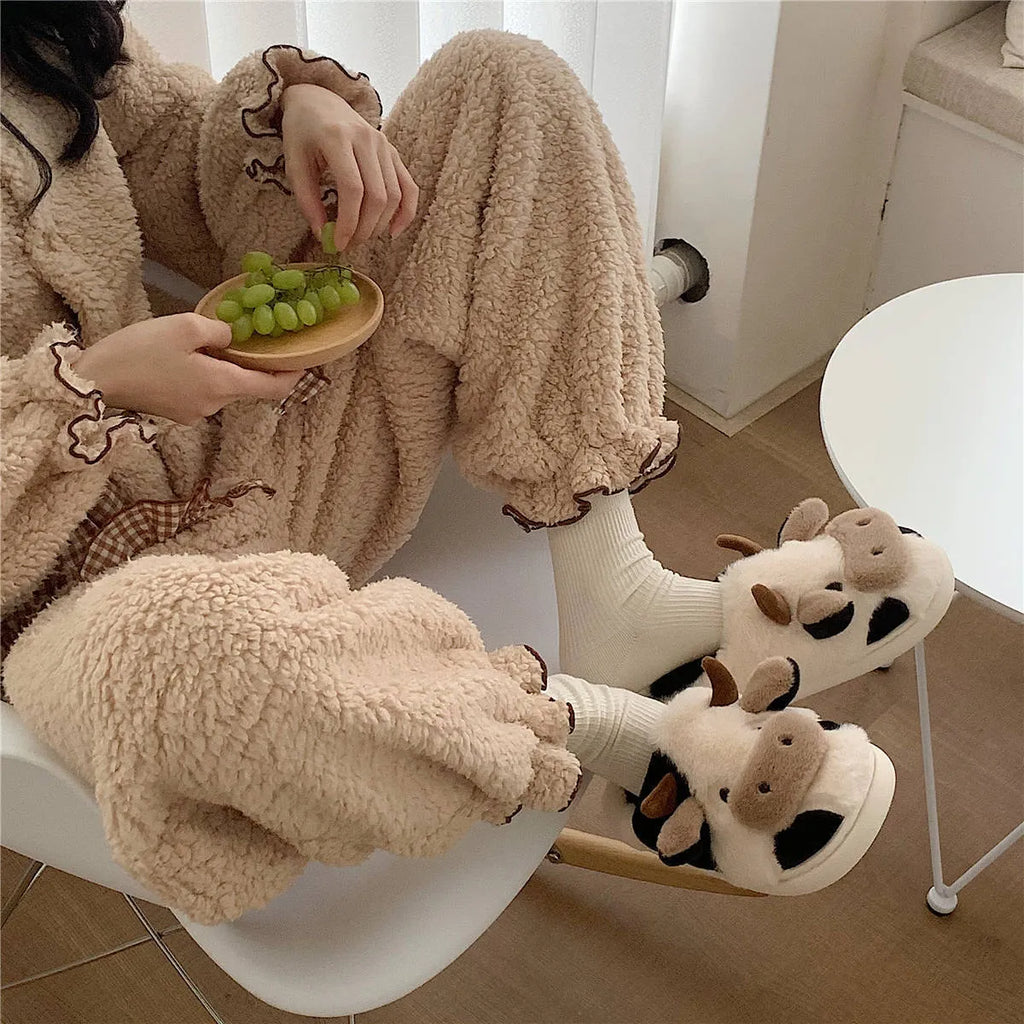 White cartoon cow slippers with plush faux fur and a textured non-slip sole.