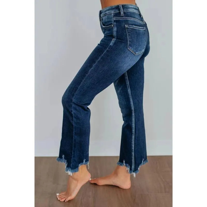 Women's dark blue denim jeans with hand-worn distressing detail on a hanger.
