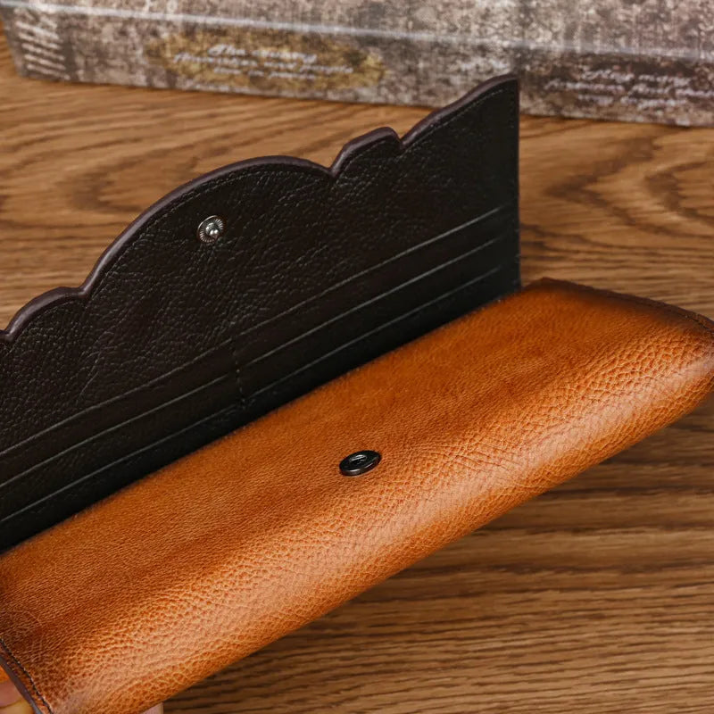Women's embossed floral tri-fold leather wallet in retro brown colour showing cowhide texture and organisational compartments.