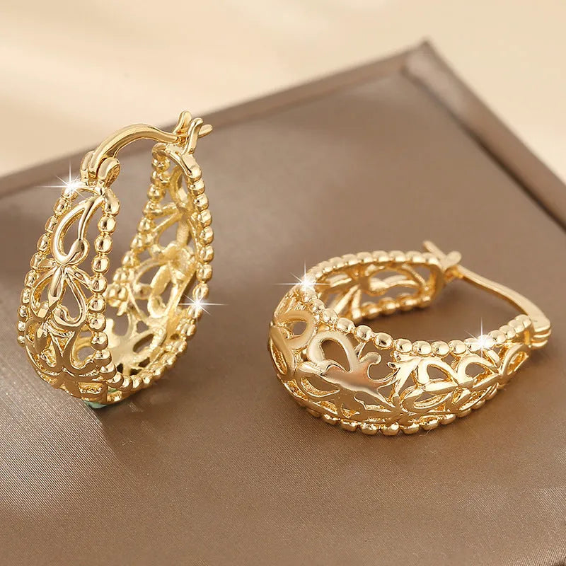 Gold copper geometric hollowed-out large earrings with round shape on neutral background