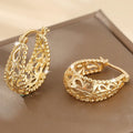 Gold copper geometric hollowed-out large earrings with round shape on neutral background