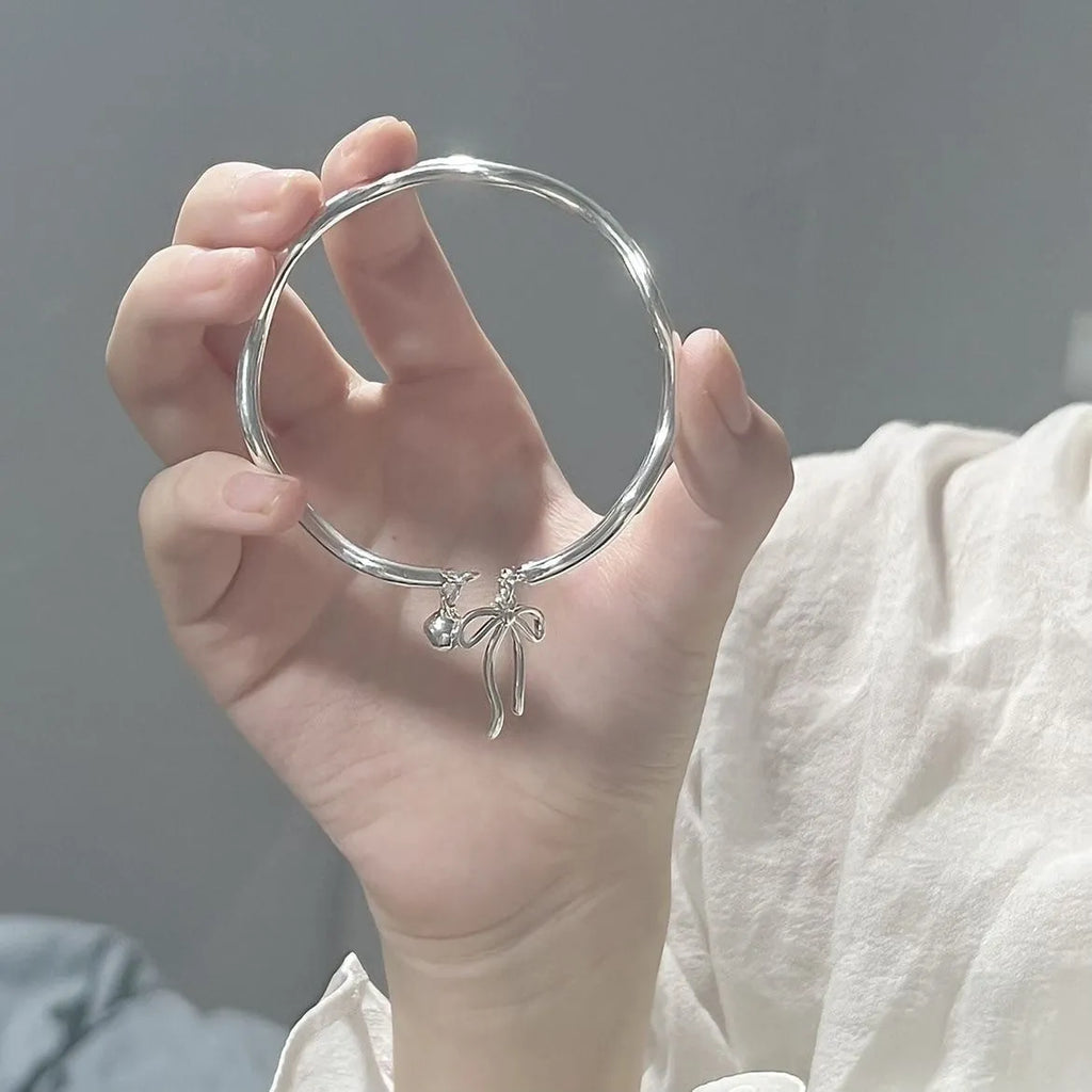 Silver adjustable bracelet with bow charm and bell opening mechanism