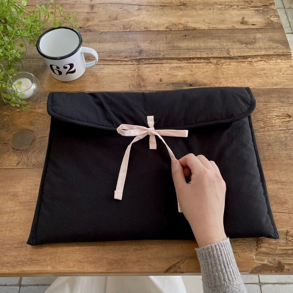 Black and white quilted women's laptop bag with striped pattern and a ballet-style bow.