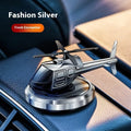 Silver metal solar-powered helicopter car ornament with rotating blades on a car dashboard.