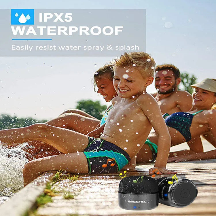 Black mini portable Bluetooth speaker with waterproof IPX7 rating on a textured surface.