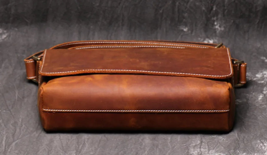 Brown vintage leather men's messenger bag with a shoulder strap showing internal organiser pockets.