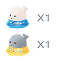 Automatic electric whale bath toy spraying water with LED lights on, floating in a baby bath.