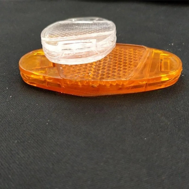 White and yellow plastic bicycle spoke reflectors measuring 7.2cm long by 3.5cm wide for night safety