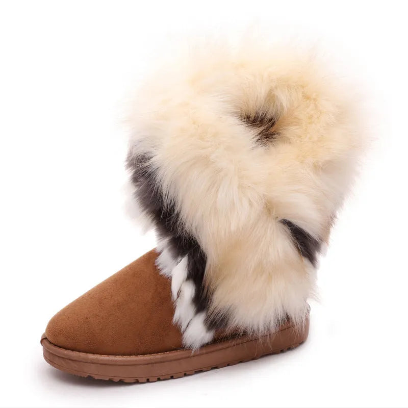 Women's winter snow boots in suede with fluffy fox fur trim and rubber sole on a snowy path