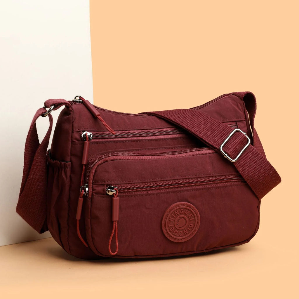 Water-repellent nylon crossbody cloth bag showing internal zipper compartments and shoulder strap