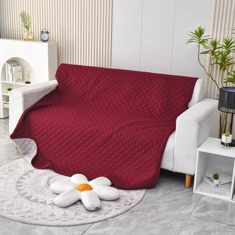 Reversible dog blanket on a sofa, showing two colour options, protecting furniture from pets.
