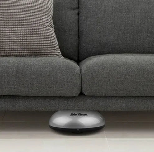 Silver-coloured compact automatic sweeping robot vacuum cleaner on a wooden floor.