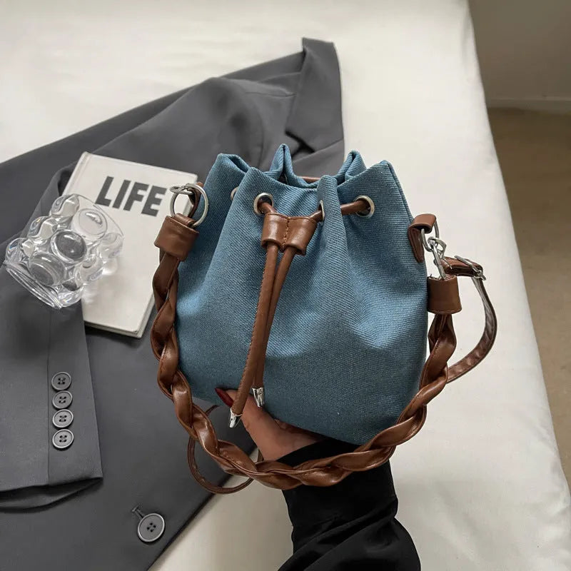 Blue one-shoulder cross body bucket bag with synthetic leather lining and hanging drop ornament