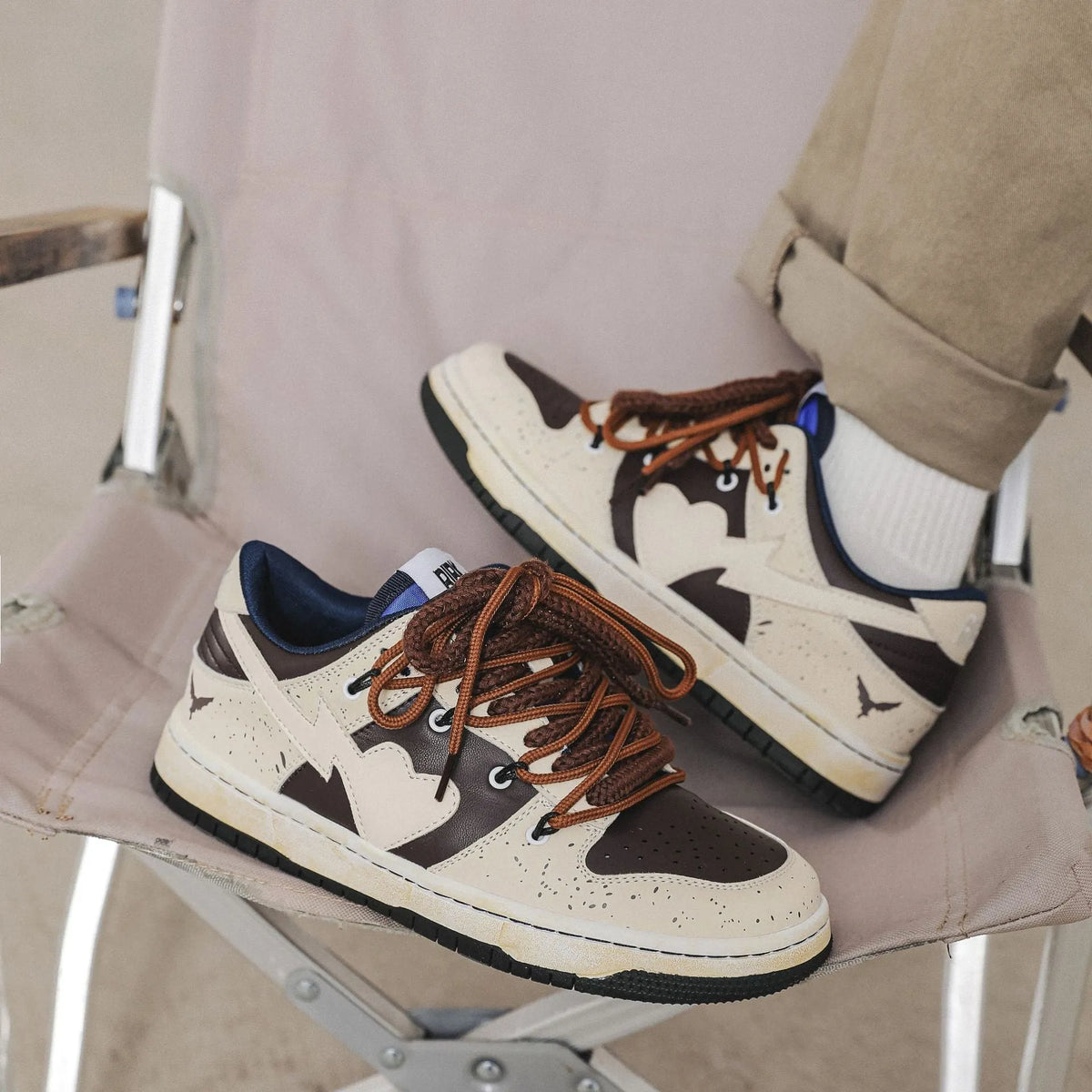 Brown low-top unisex casual sneakers with leather stitching, rubber sole, and front lace-up