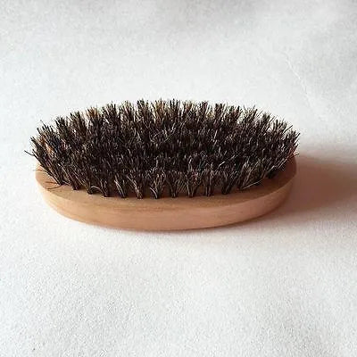 Natural boar beard brush for men in black finish with dense bristles on a table