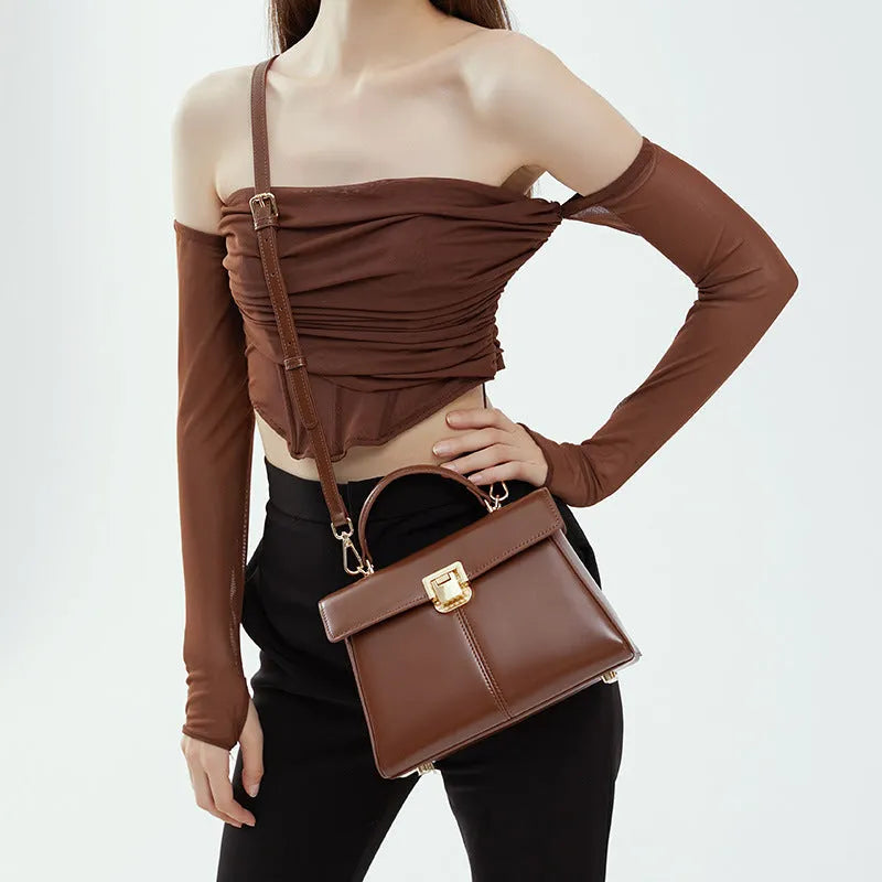 Women's black leather shoulder bag with clasp closure and adjustable strap showing interior organisation