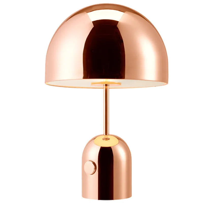 Mushroom-shaped table lamp with a metal base in rose gold finish on a wooden table.