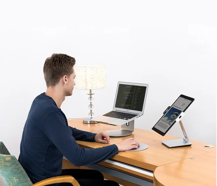 Silver aluminium folding phone and tablet stand on a desk, holding a tablet