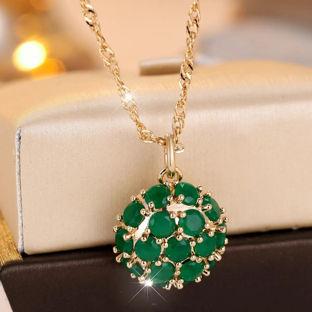 Round emerald pendant necklace with diamond surround on champagne gold chain