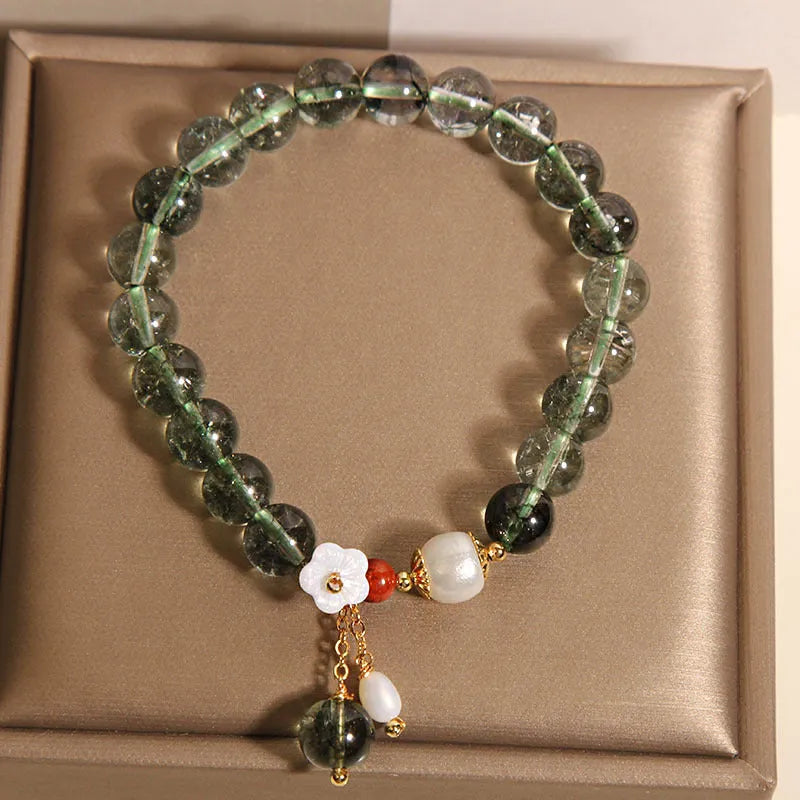Green phantom quartz crystal bracelet with a silver shell flower charm on a model's wrist.