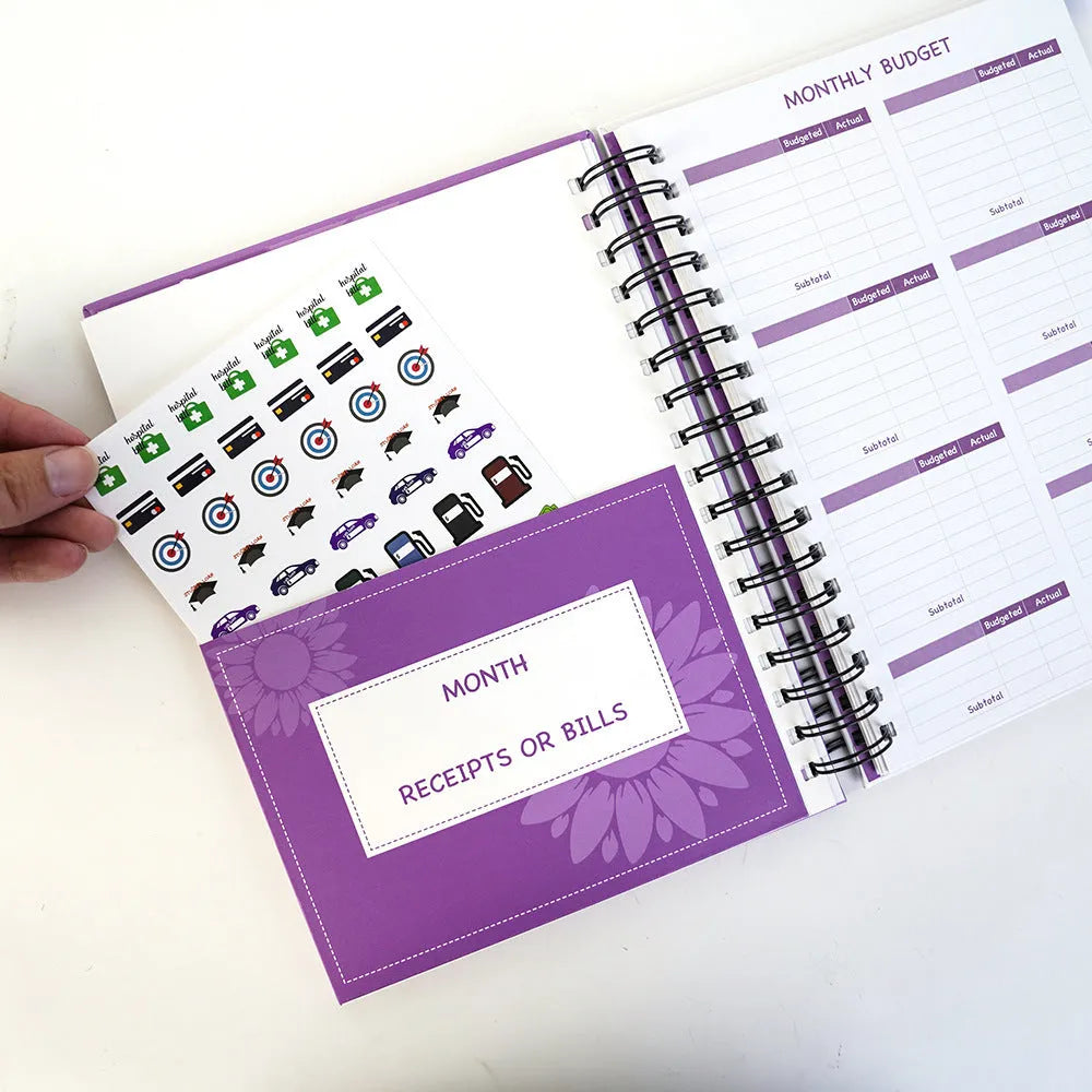 Purple coil-bound budget book with stickers and paper clips for monthly financial planning