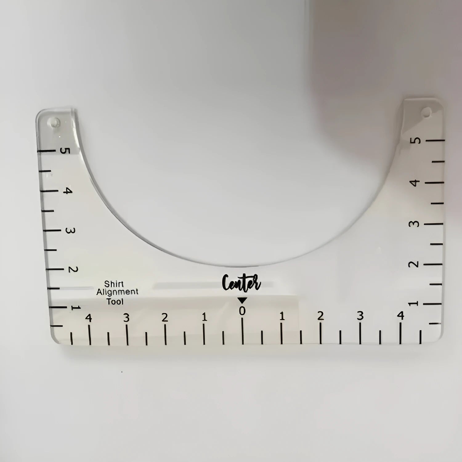 Transparent acrylic sewing ruler for aligning T-shirt designs, measuring 10 by 6 inches.