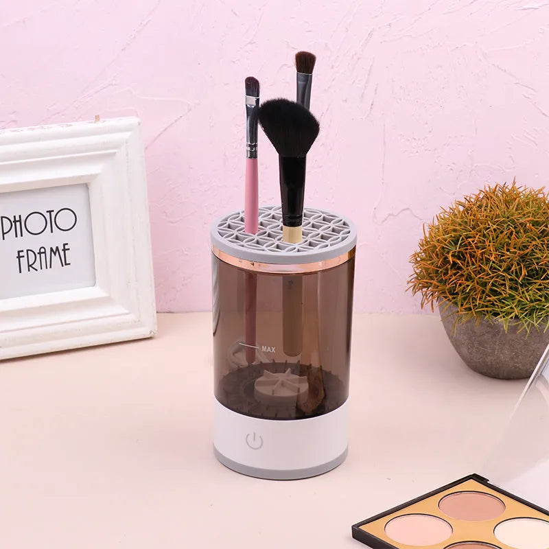 Grey and white electric makeup brush cleaner machine with USB cable on a white background