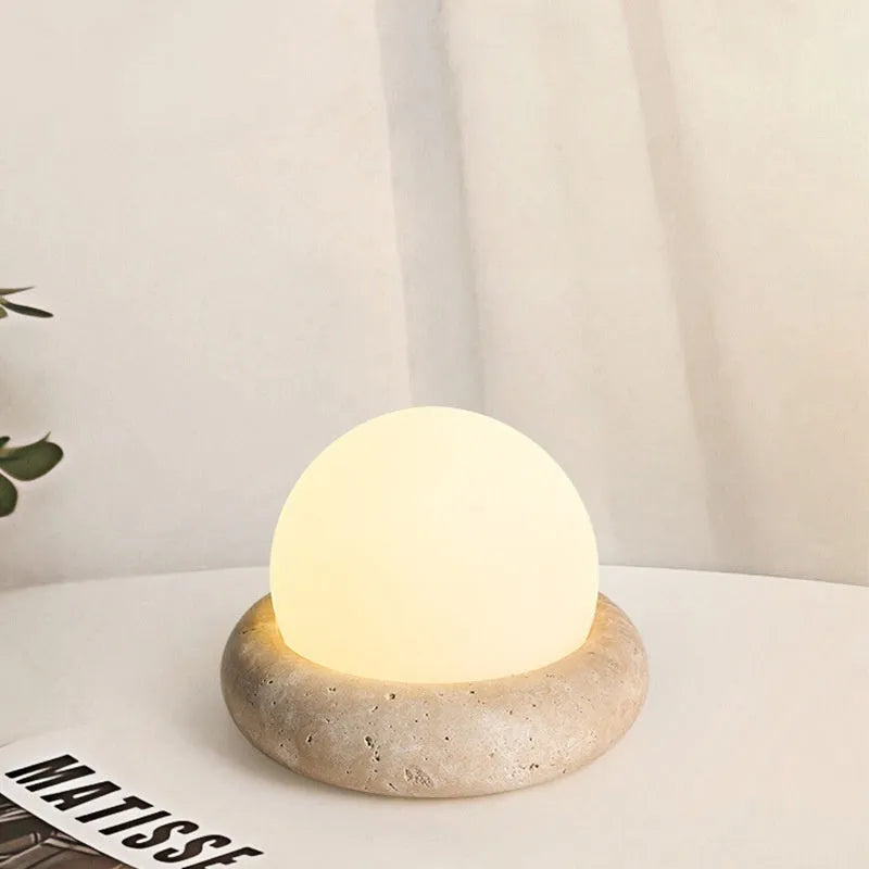 Cream coloured bedside night lamp with remote control on wooden table