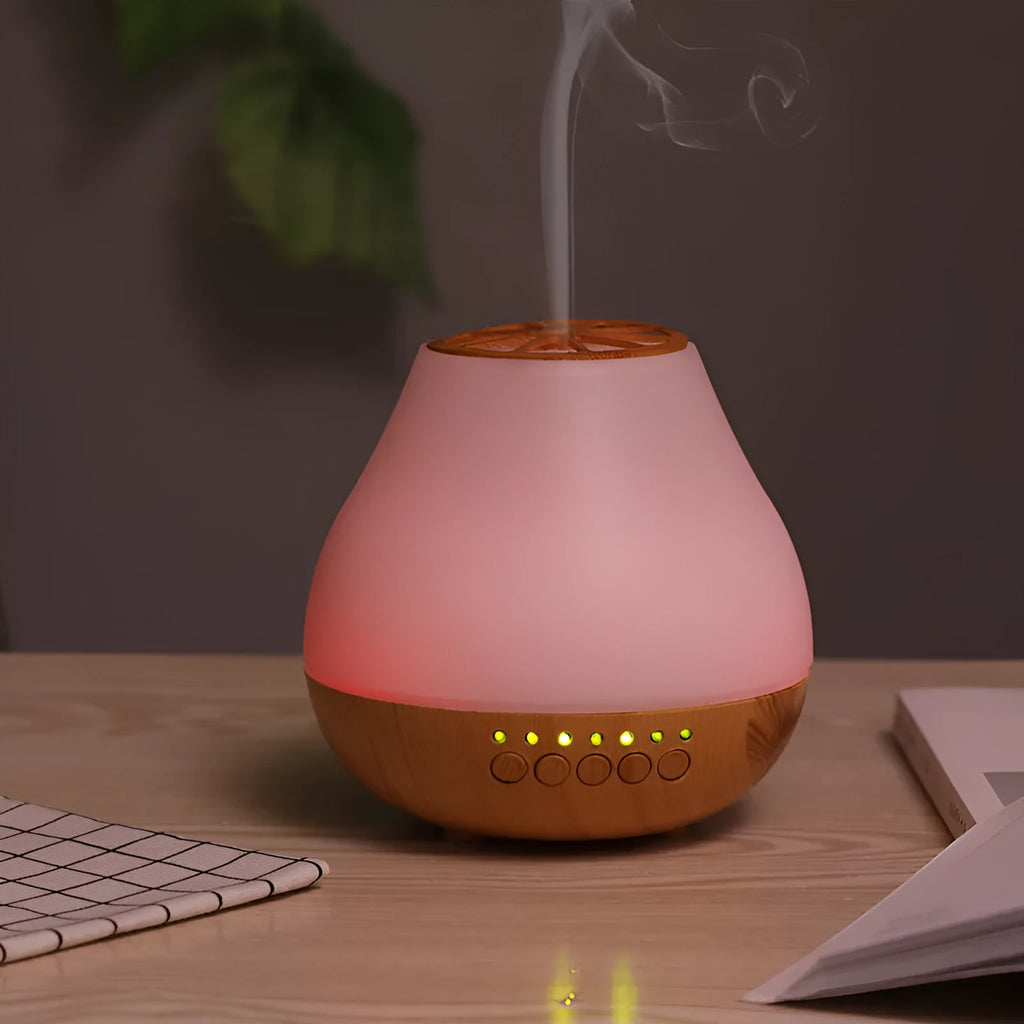 Wood grain finish USB aroma diffuser on a table next to a bottle of essential oil.