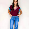 Burgundy loose longline women's sweater with V neckline and cuffed short sleeves with contrast trim.