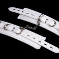 White PU sponge BDSM bondage set showing handcuffs, foot cuffs, and a neck scarf.