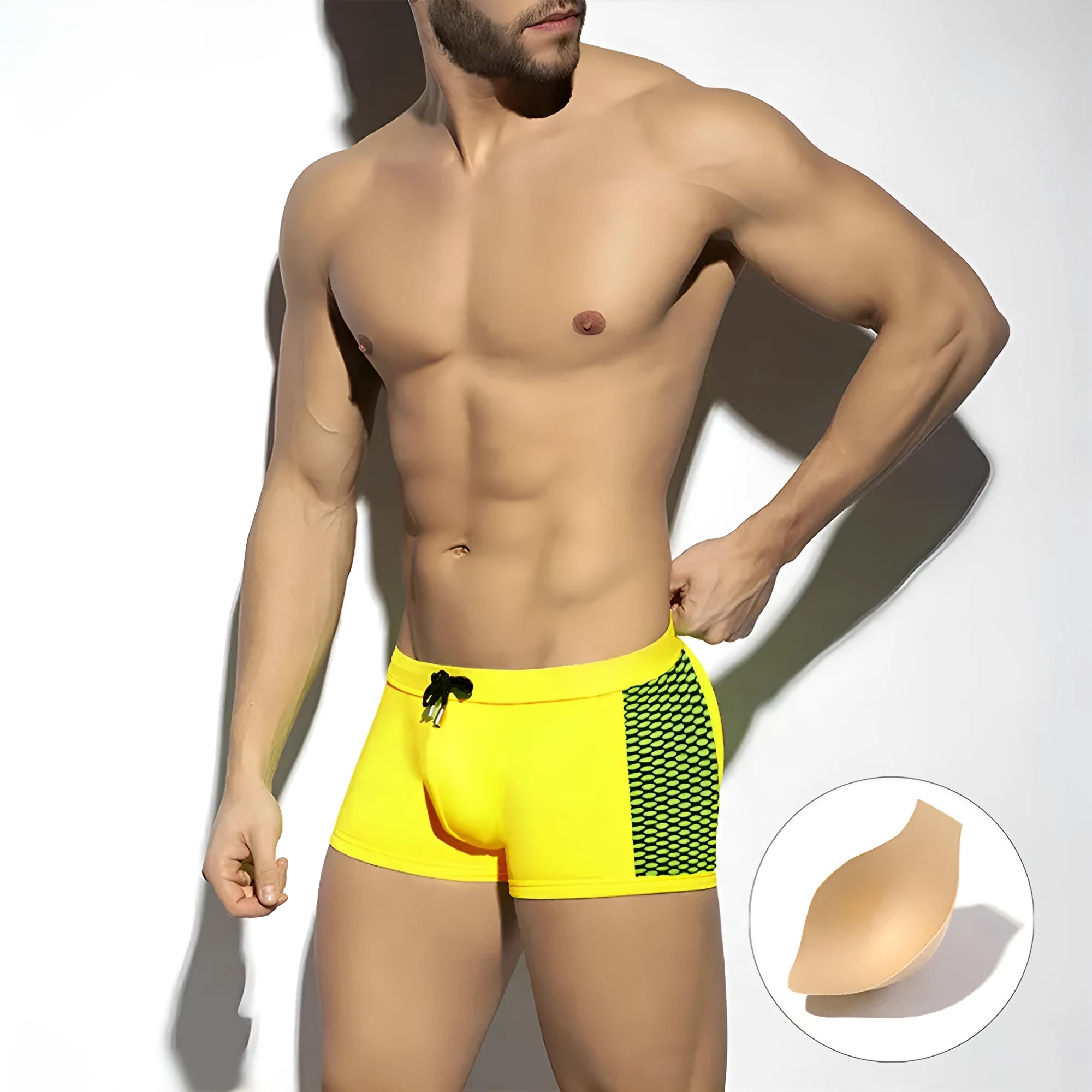 Men's black polka dot swimming boxers with a dark blue ribbon trim on a grey background.