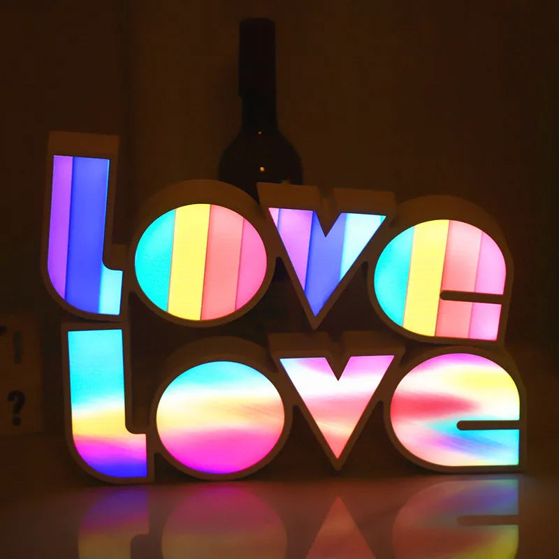 Colourful LED LOVE light decoration with rainbow lampshade on a table.