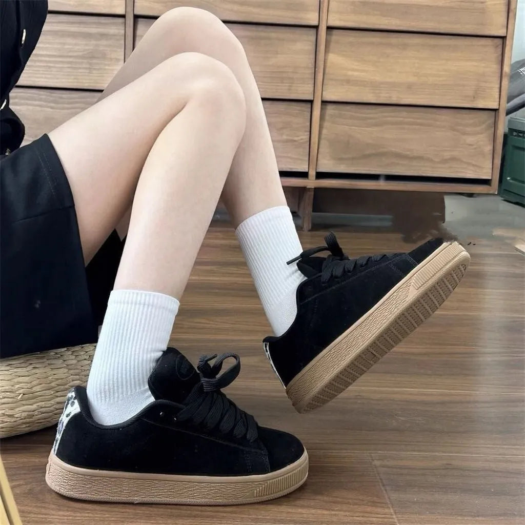 Black retro low-top sneakers with a platform sole and front lace-up closure on a white background.