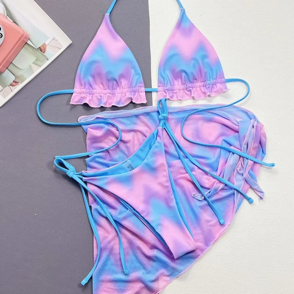Women's tie-dye pattern bikini set with matching skirt on a neutral background.