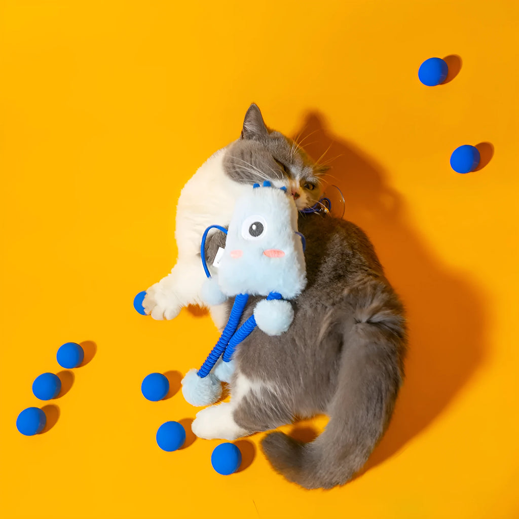 Blue plush cat toy with a telescopic elastic rope and a mint-coloured bell ring on a white surface.