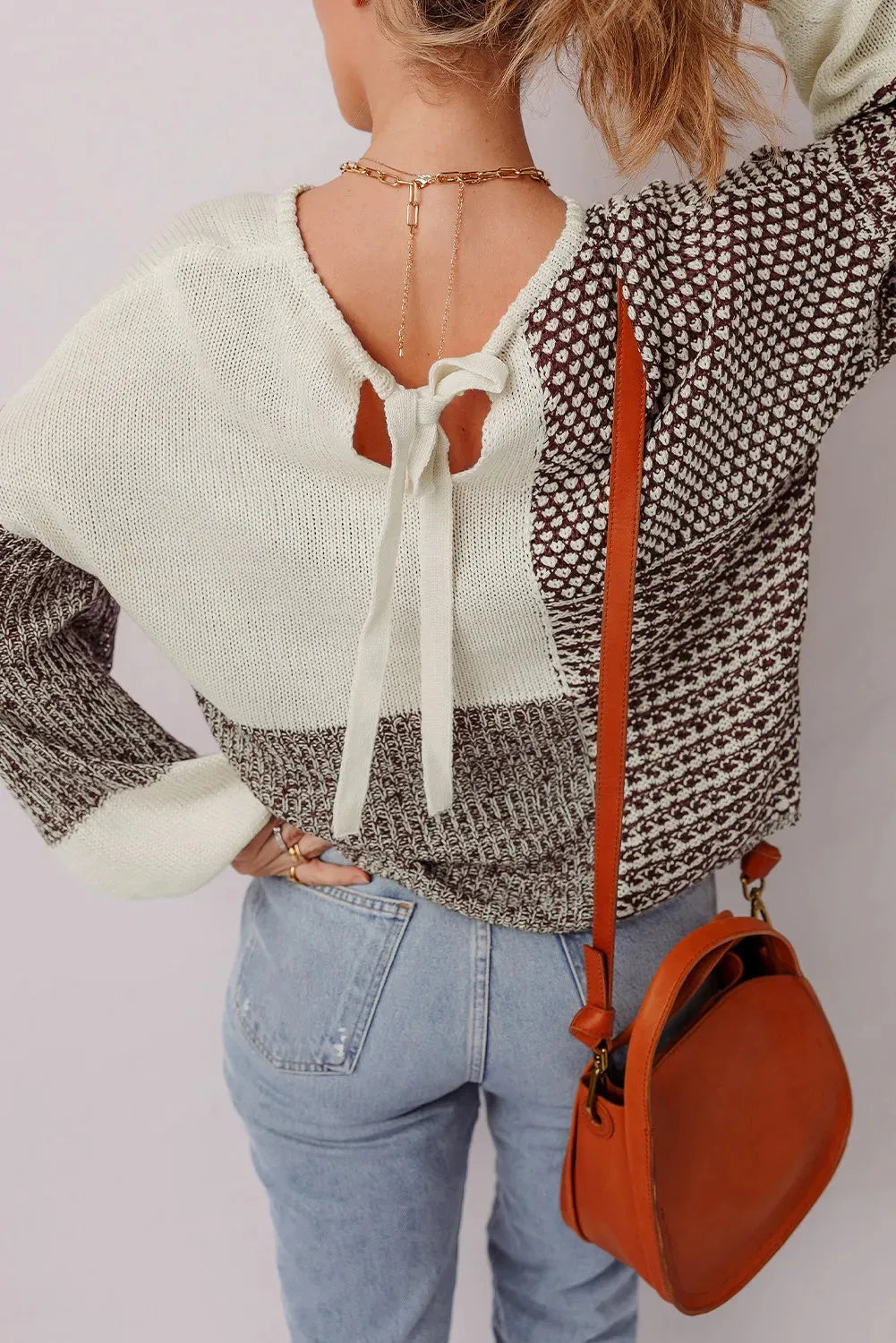 Dark khaki loose sweater with colour block design and back tie, on a model.