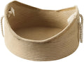 Wicker cat bed basket with a corrugated scratching board inside, shown in a home setting.