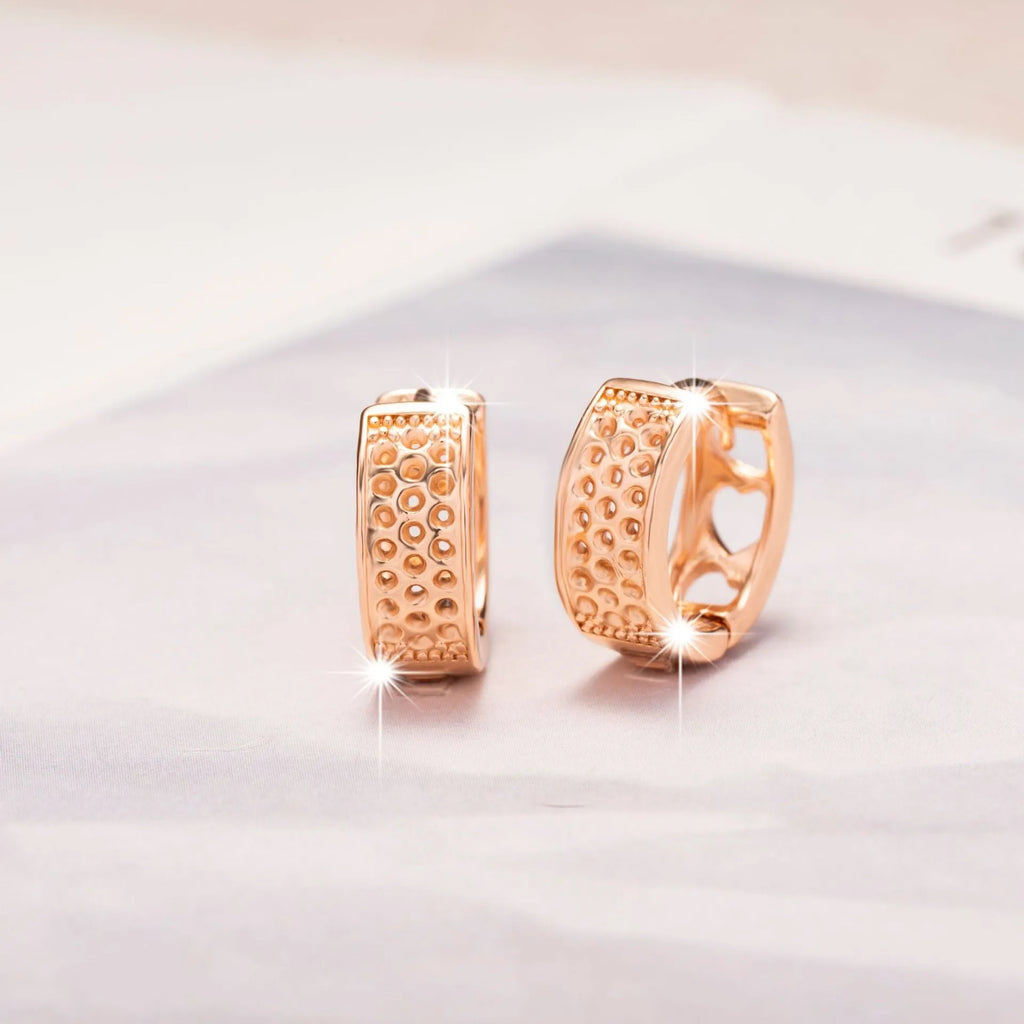 Rose gold coloured earrings with three hollow heart shapes arranged in circular pattern