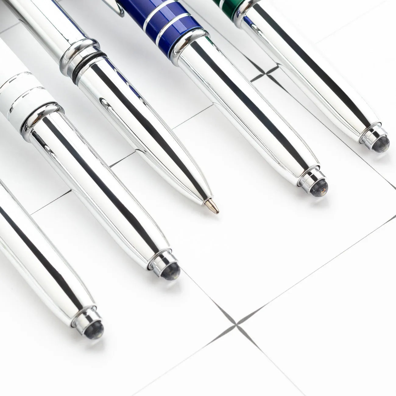 Red metal capacitive stylus and ballpoint pen with a built-in LED light on a desk next to a tablet.