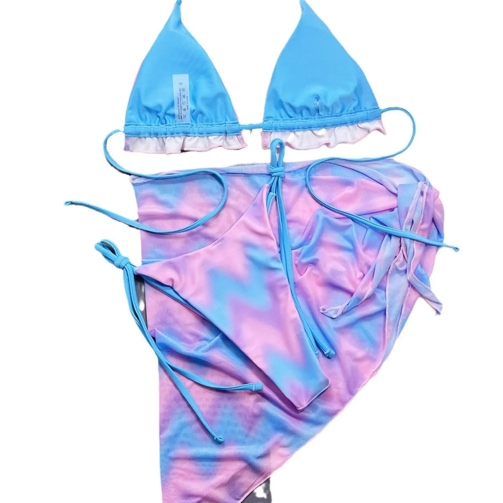 Women's tie-dye pattern bikini set with matching skirt on a neutral background.