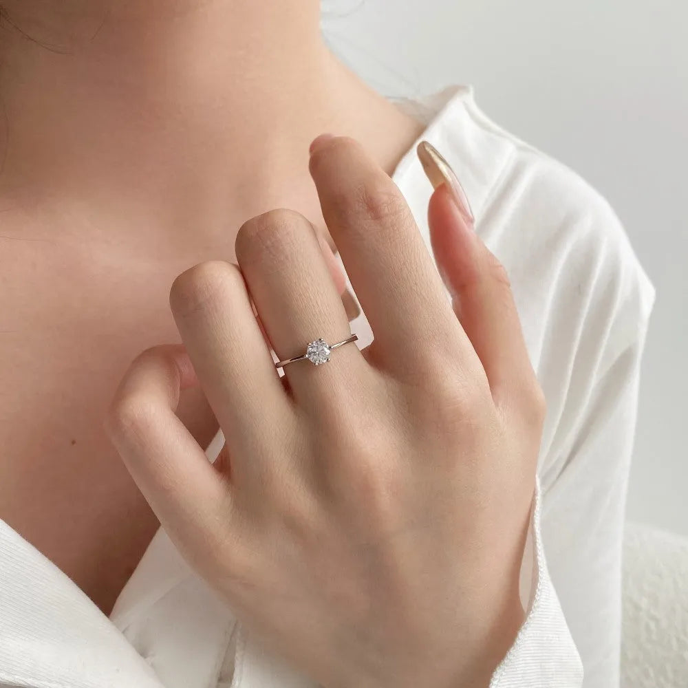 Sterling silver ring with six-claw zircon setting and open mouth adjustable band on white background