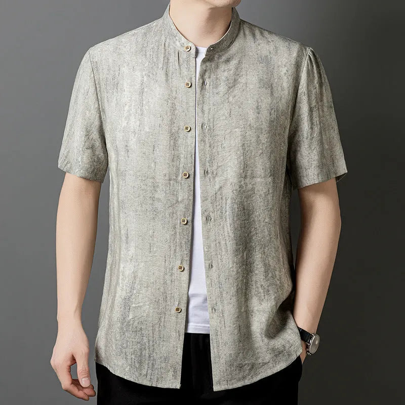 Man wearing a loose grey short sleeve cardigan shirt with a stand collar.
